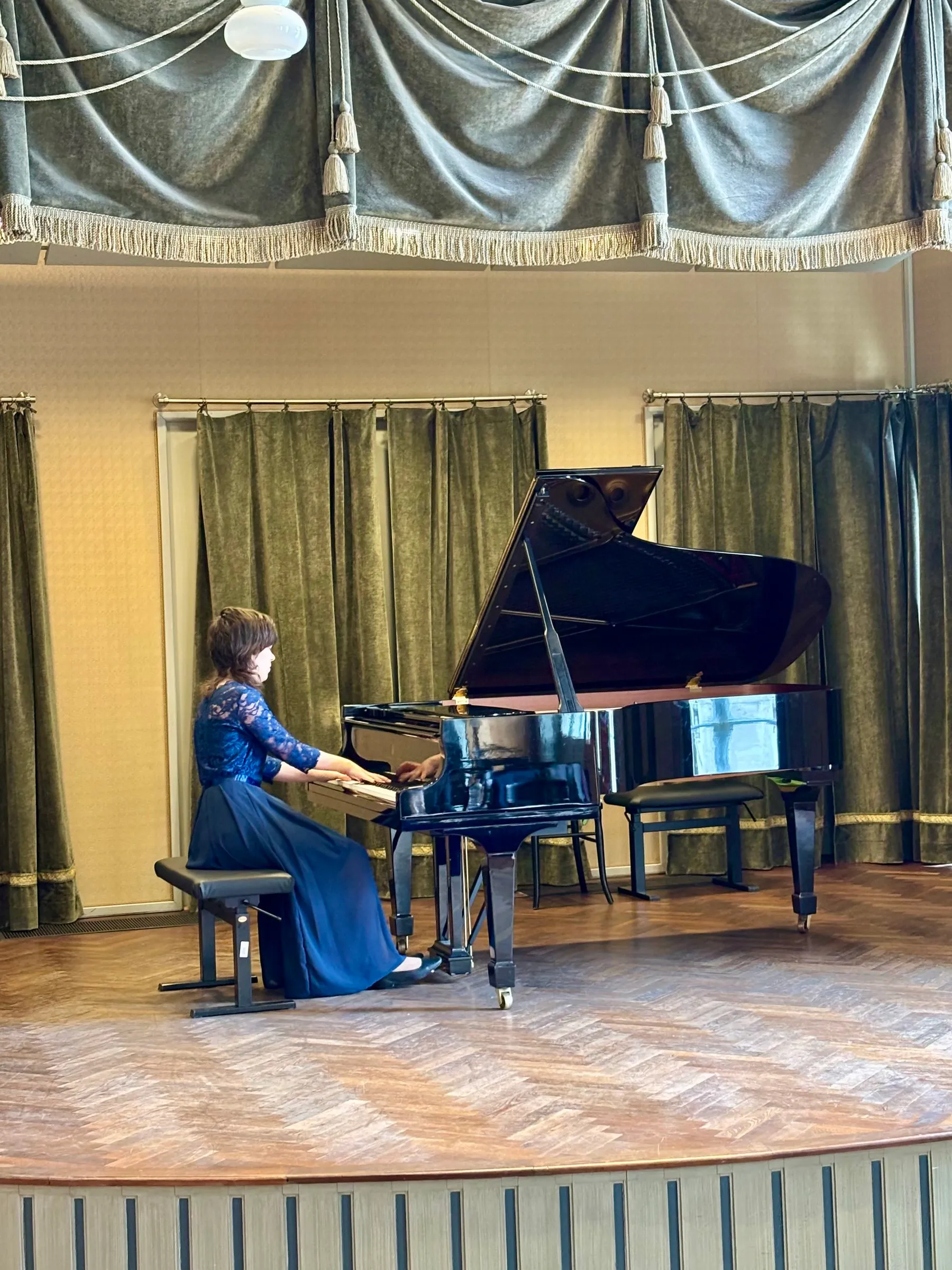 A pianist in a blue evening dress plays the grand piano at the Liszt Academy, Budapest